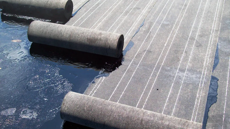 Bitumen felt rolls being torch-applied to a flat roof